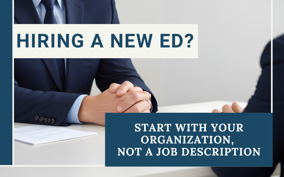 Two professionals seated across from each other at a desk with documents, with text reading Hiring a New ED? Start With Your Organization, Not a Job Description