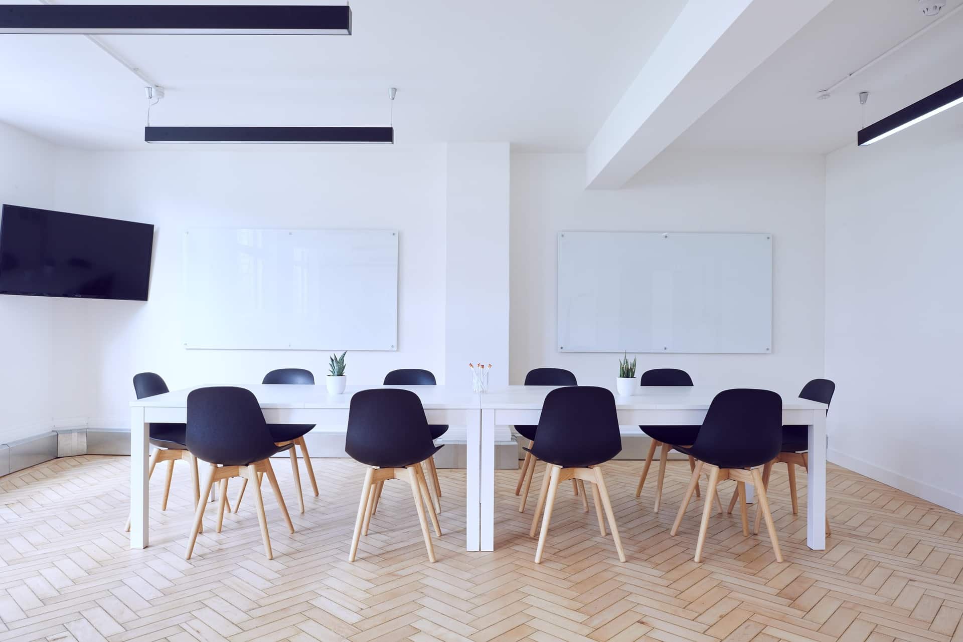 ebersmith-full-board-evaluation-room A spacious, modern conference room with a herringbone floor and whiteboards, illustrating the comprehensive setting for a Full Board Assessment by ebersmith coaching and consulting