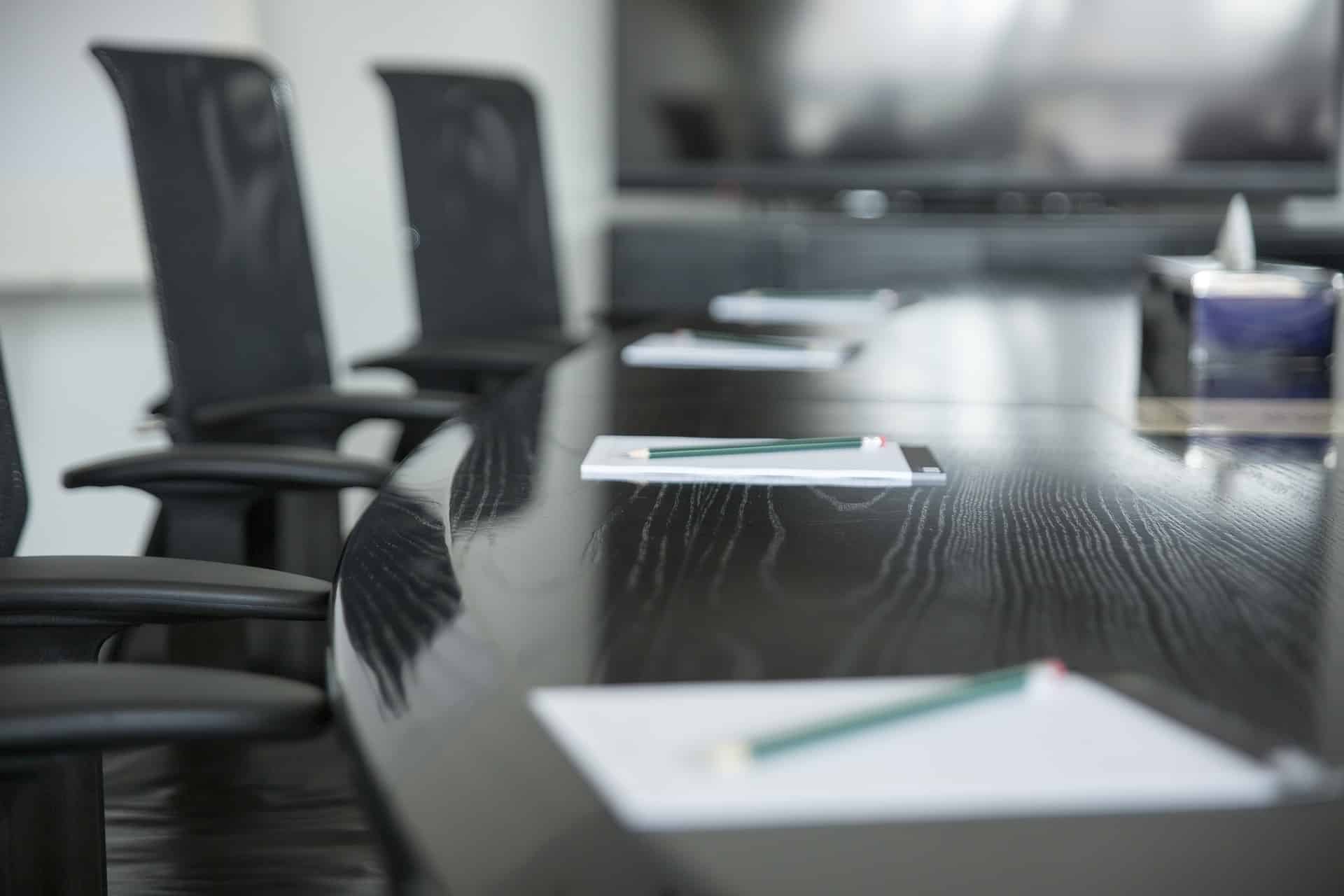 A close-up, modern executive boardroom table with high-end chairs, representing the flagship Board Build™ consulting service by ebersmith